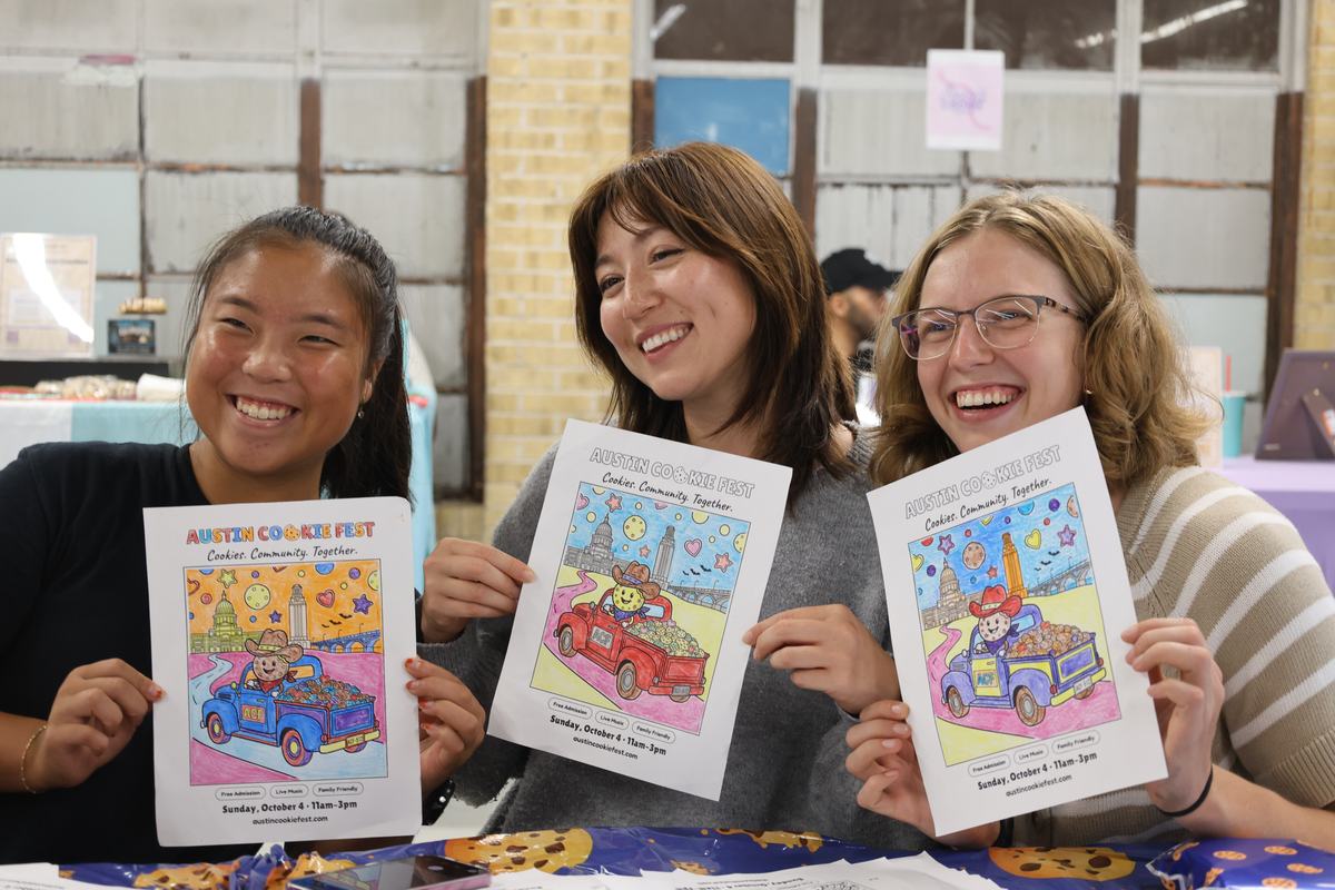 Three visitors holding up their Austin Cookie Fest coloring sheets
